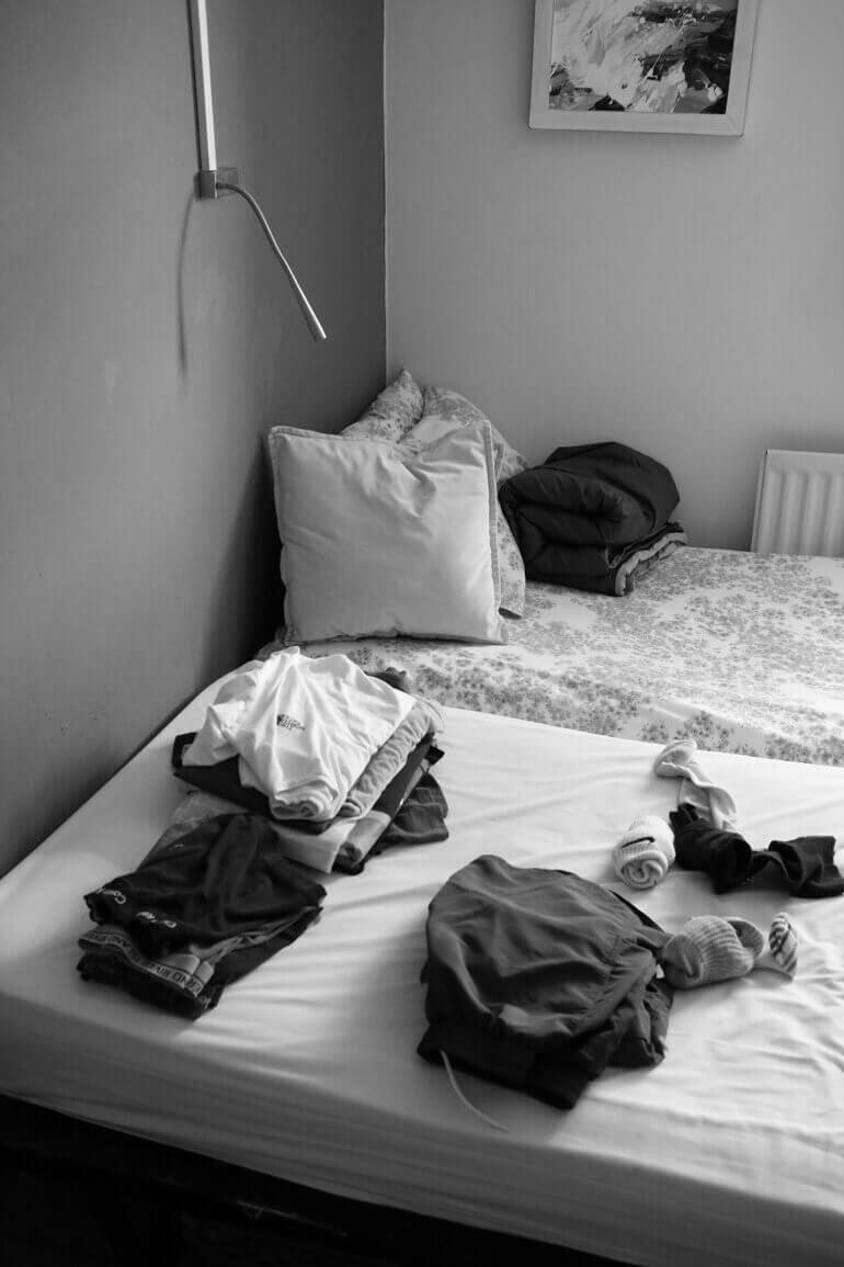 Black and white Winchester Churches Night Shelter bedroom with folded clothes inside a hostel room